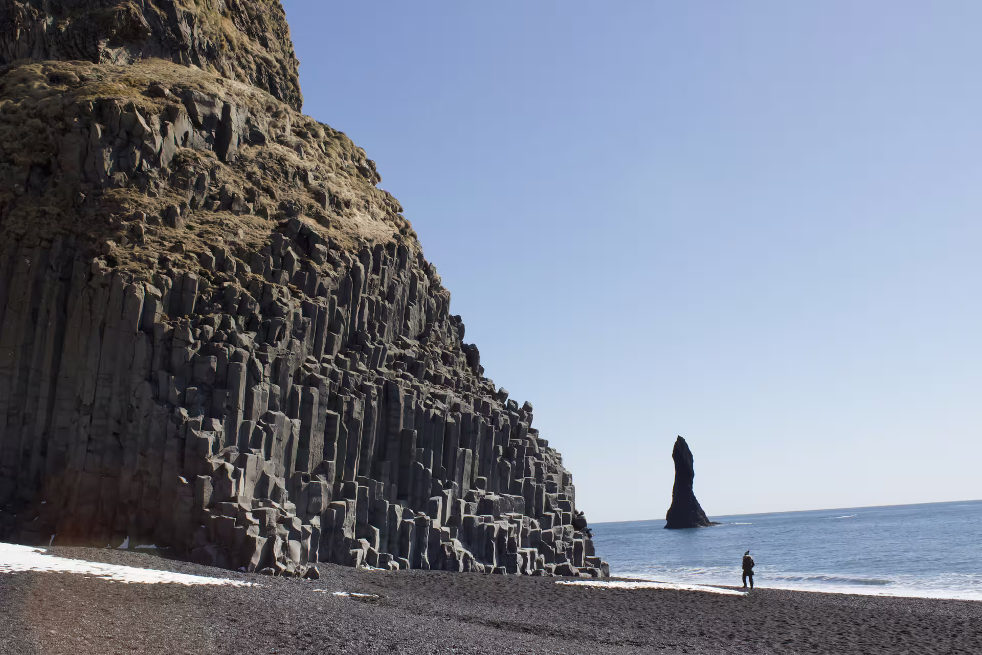 Basalt column cliffs and sea stack at Reynisfjara black sand beach on Iceland's south coast