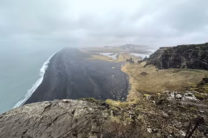 Aerial view of Reynisfjara black sand beach along Iceland's South Coast with dramatic cliffs and ocean waves