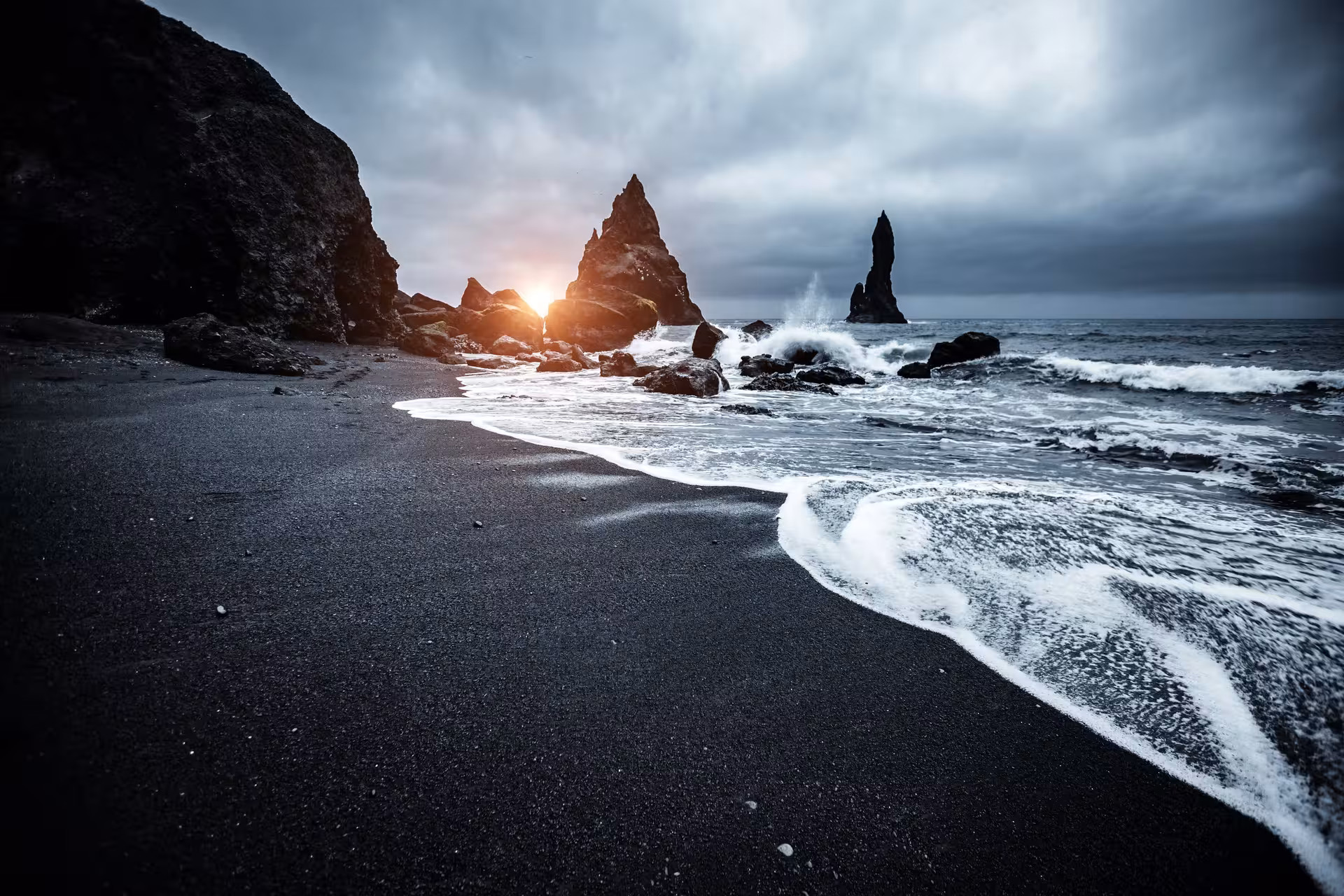 Sunset over Reynisfjara Black Sand Beach with dramatic sea stacks and ocean waves, perfect for Iceland tours.