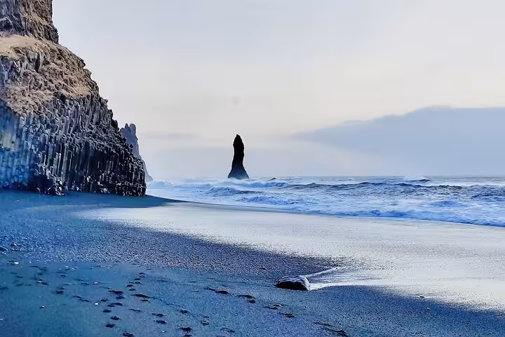 Black sand beach with basalt columns and sea stack at Reynisfjara near Vik, Iceland
