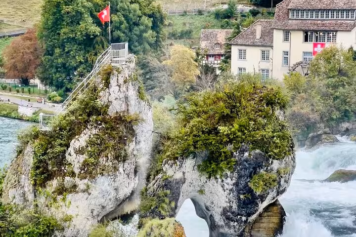 Rhine Falls rock viewpoint with Swiss flag and misty cascades, highlight of half-day luxury tour in Schaffhausen