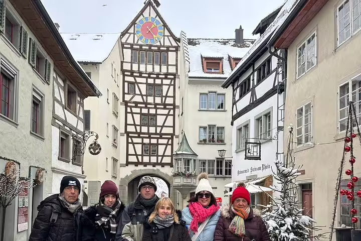 Visitors enjoying a snowy day at the iconic clock tower in Stein am Rhein during a private day trip from Zurich.