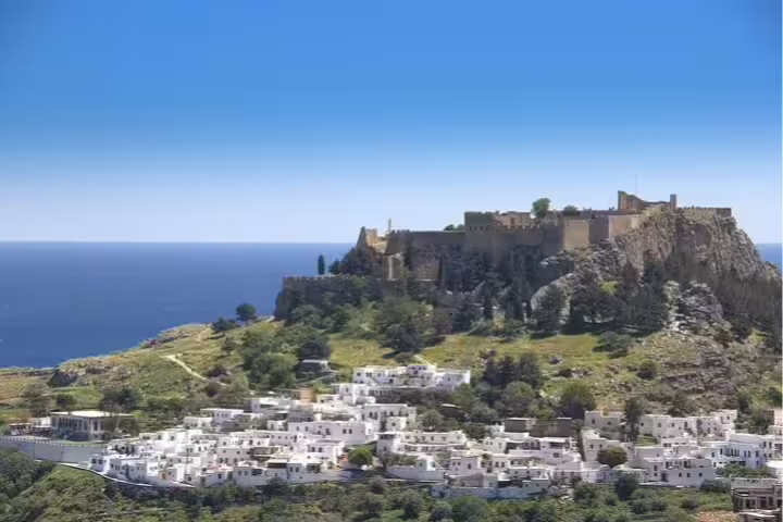 Scenic view of Lindos Acropolis and whitewashed village buildings under a clear sky, perfect for a Rhodes wine tasting tour.