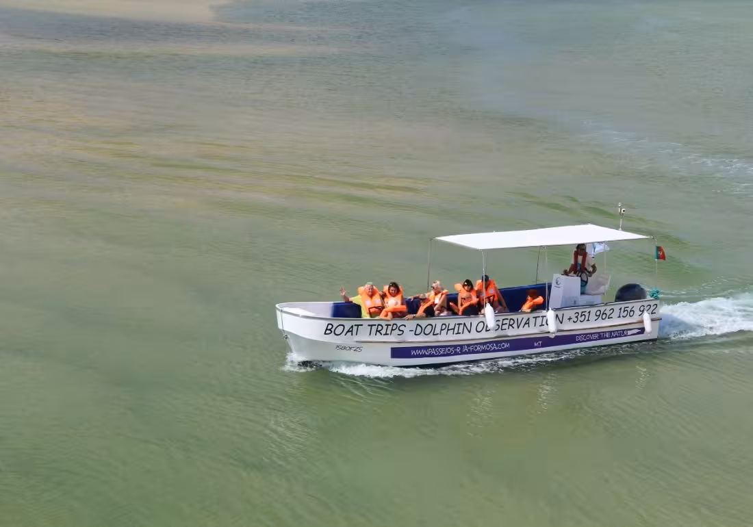 Tourists in orange life jackets enjoying a Ria Formosa boat tour for dolphin observation in Algarve Portugal