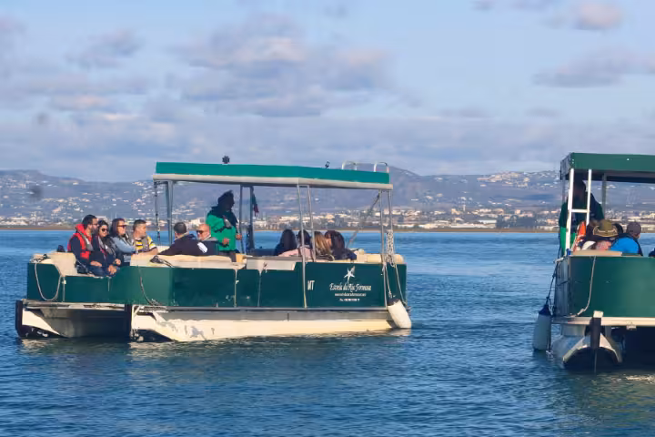Passengers on a Ria Formosa boat tour cruising the lagoon near Faro, Algarve, with scenic coastline views