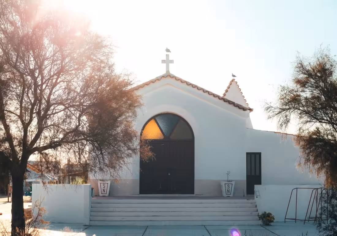 Whitewashed chapel with a cross on a sun-drenched island stop during a Ria Formosa Natural Park boat tour