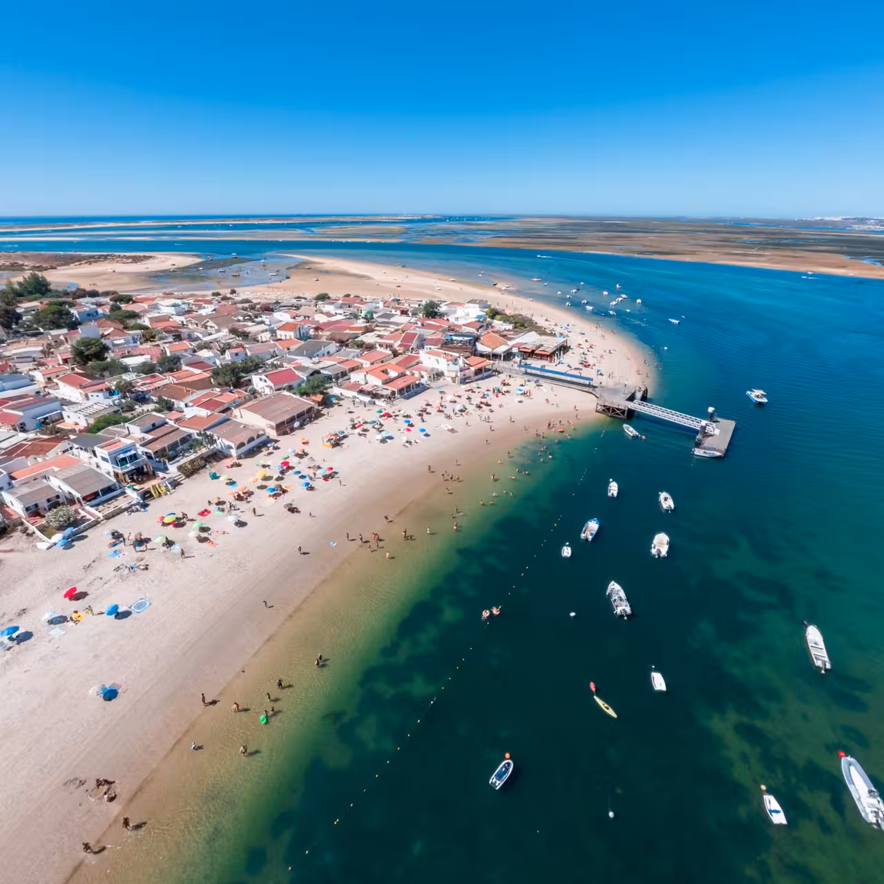 Drone view of Ria Formosa waterfront village, beach and moored boats, perfect for a 2-hour lagoon tour