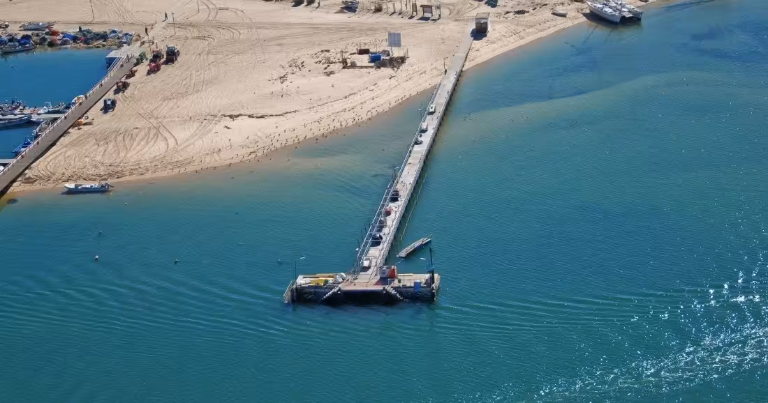 Aerial drone view of a sandy island pier with turquoise waters during a Ria Formosa Natural Park boat tour stop