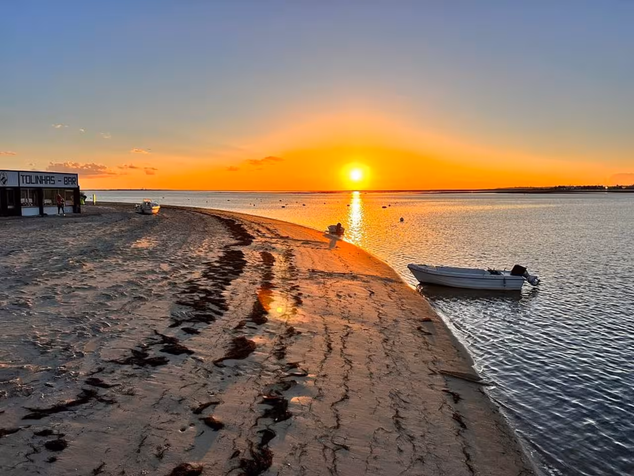 Golden sunset over Ria Formosa lagoon with sandy spit and small boats, Algarve sunset tour experience