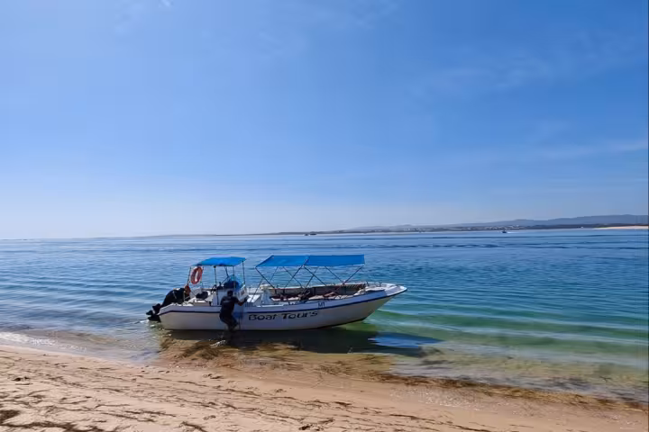 Ria Formosa tour boat moored by a sandy island beach, Algarve, perfect stop on a 2-hour lagoon cruise