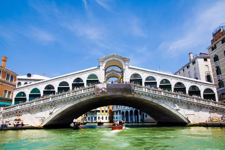 Rialto Bridge over the Grand Canal in Venice with tourists and boats below on a sunny day