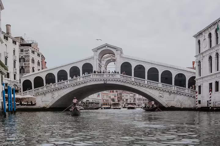 View of the iconic Rialto Bridge over the Grand Canal in Venice, featuring gondolas and historic architecture.