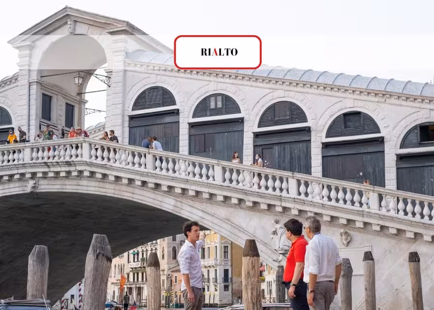 Visitors admire the historic Rialto Bridge in Venice, capturing its architectural beauty on a small group tour.