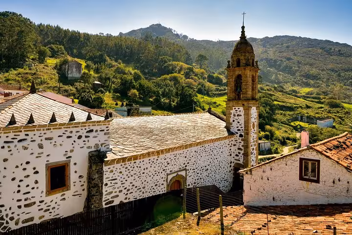 Historic stone church surrounded by verdant hills in Rías Altas, showcasing cultural landmarks on Santiago tours.