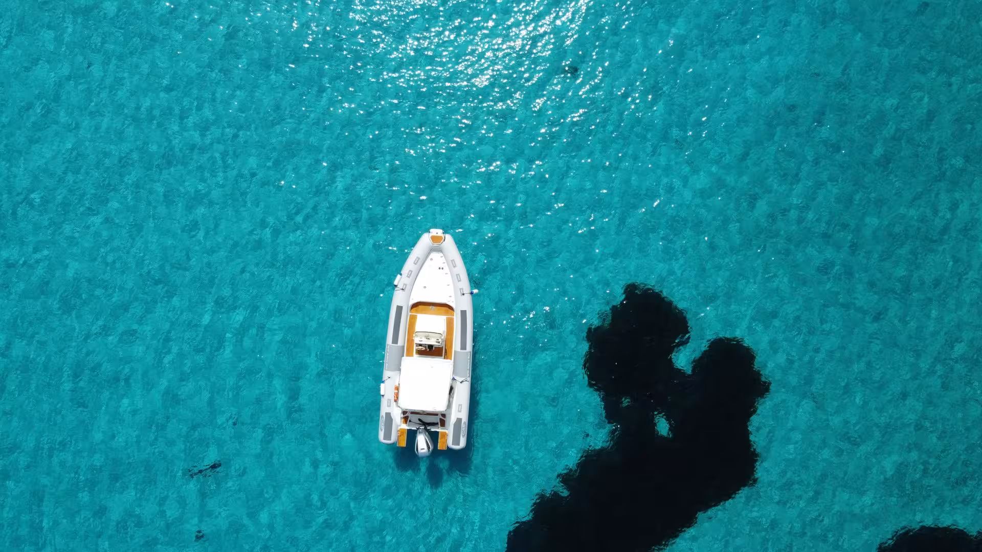 Aerial view of a RIB boat on the sparkling turquoise waters of the Gulf of Asinara near Stintino.