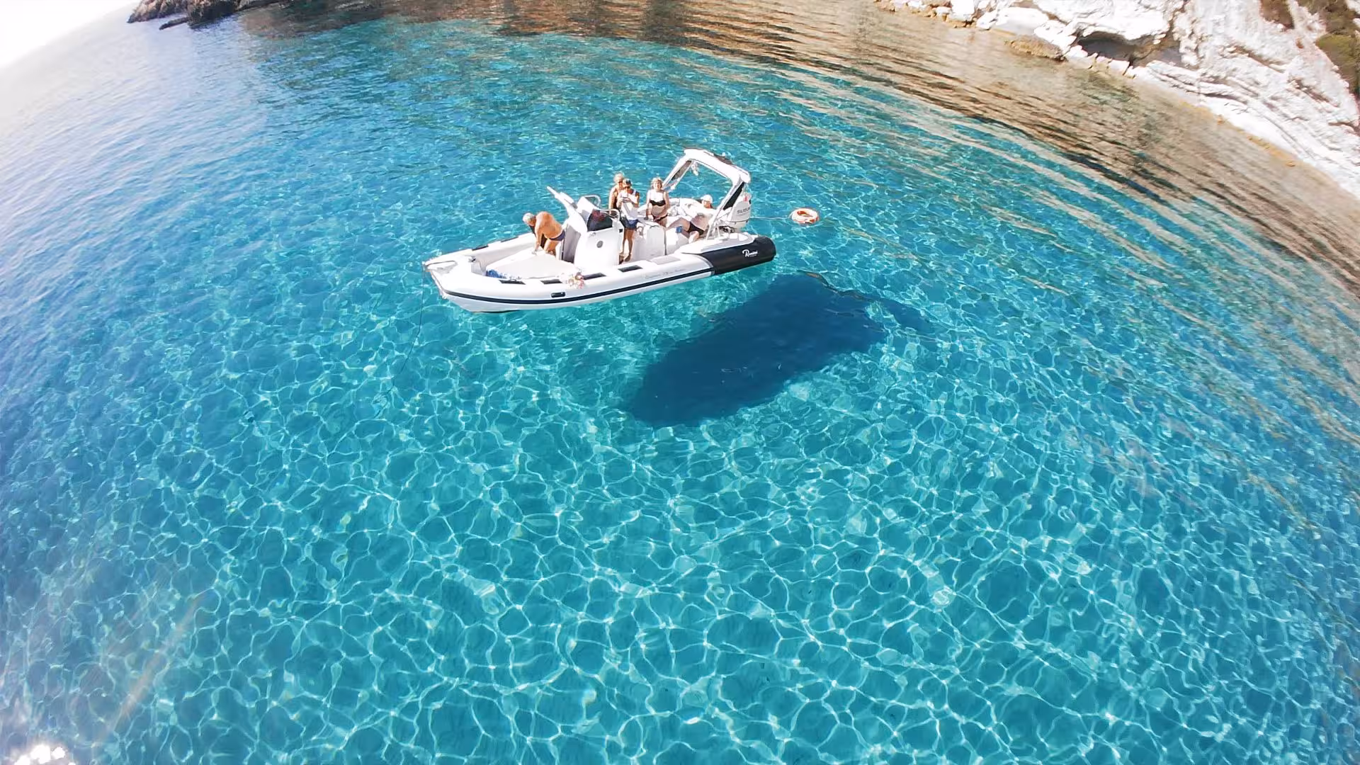 Aerial view of a RIB boat with tourists on crystal-clear waters near Carloforte.