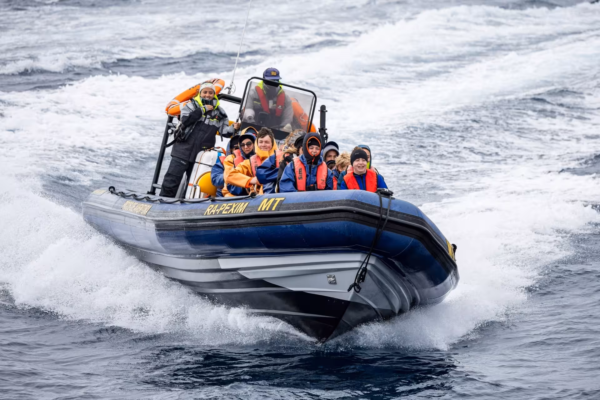Guests in life jackets ride a fast RIB speedboat through ocean waves on a full-day maritime tour with lunch