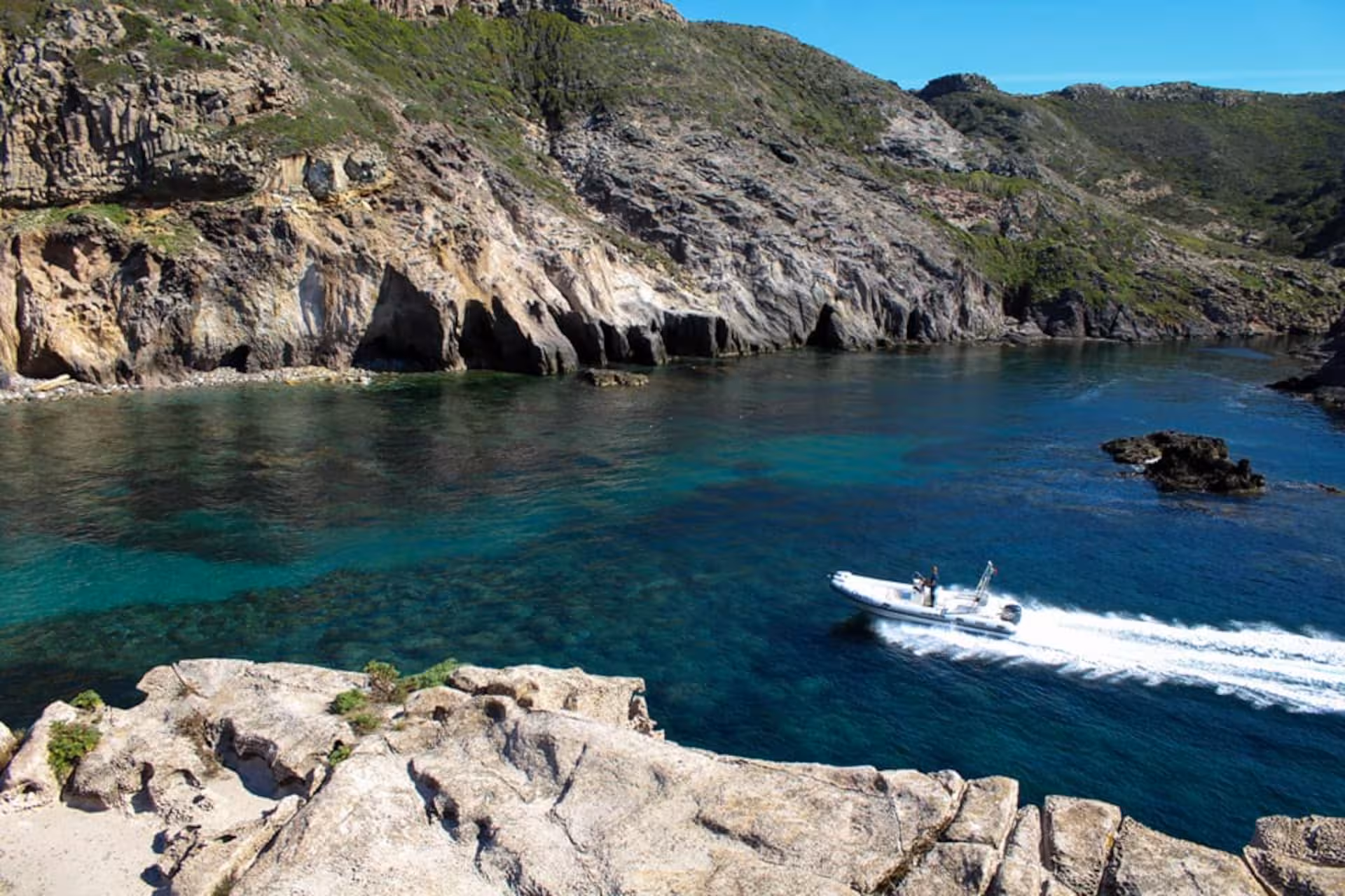RIB speeding through azure waters along rocky cliffs, showcasing stunning landscapes of the Carloforte and Masua tour.