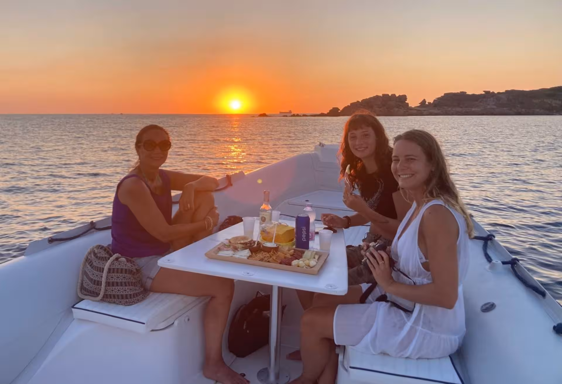 Group enjoying a sunset meal on a boat tour between Carloforte and Masua from Sant'Antioco.
