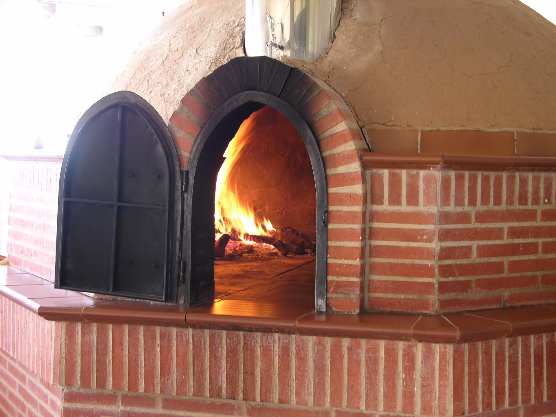 Traditional brick oven with open fire at a Ribera del Duero winery, ideal for authentic culinary experiences.