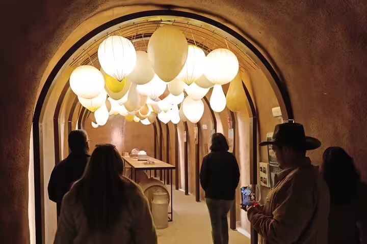 Travelers enjoy a warmly lit wine cellar tour at a Ribera del Duero winery, showcasing unique architecture.