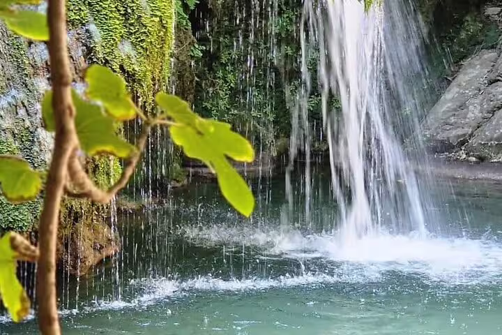 Serene view of water cascading at Richti Waterfall, surrounded by lush greenery, ideal for nature lovers.