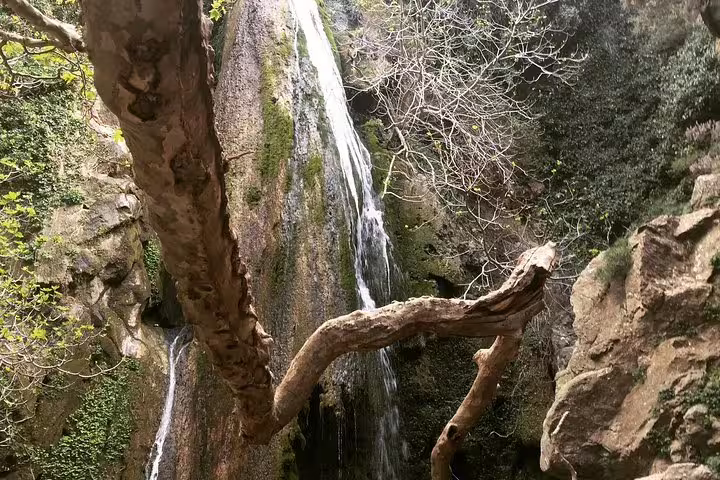 Scenic view of Richtis Waterfall cascading down mossy rocks, surrounded by lush greenery on Crete's north coast.