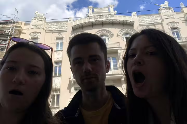 Three tourists taking a selfie in front of ornate Art Nouveau building facade in Riga