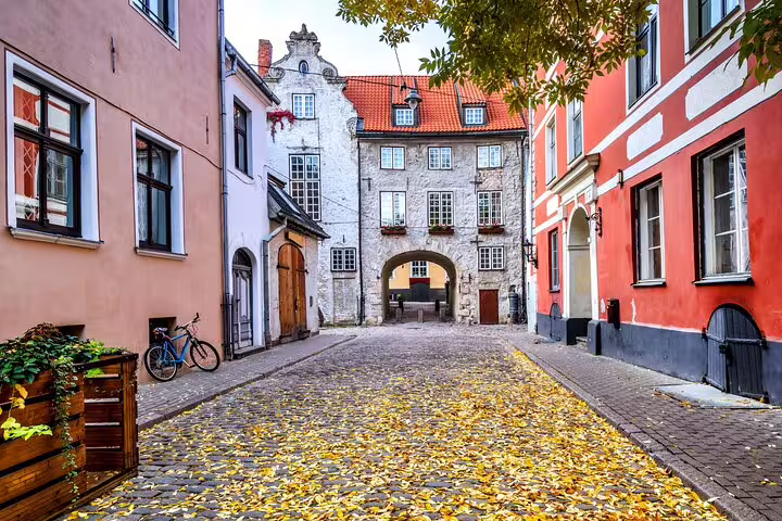 Cobblestone street with autumn leaves in Riga's Old Town, colorful historic buildings and archway