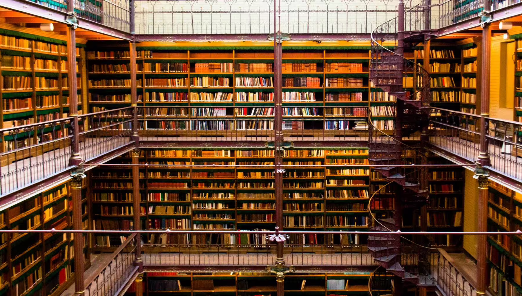 Stunning view of the Rijksmuseum library with towering bookshelves and spiral staircase, featured in private guided tours.