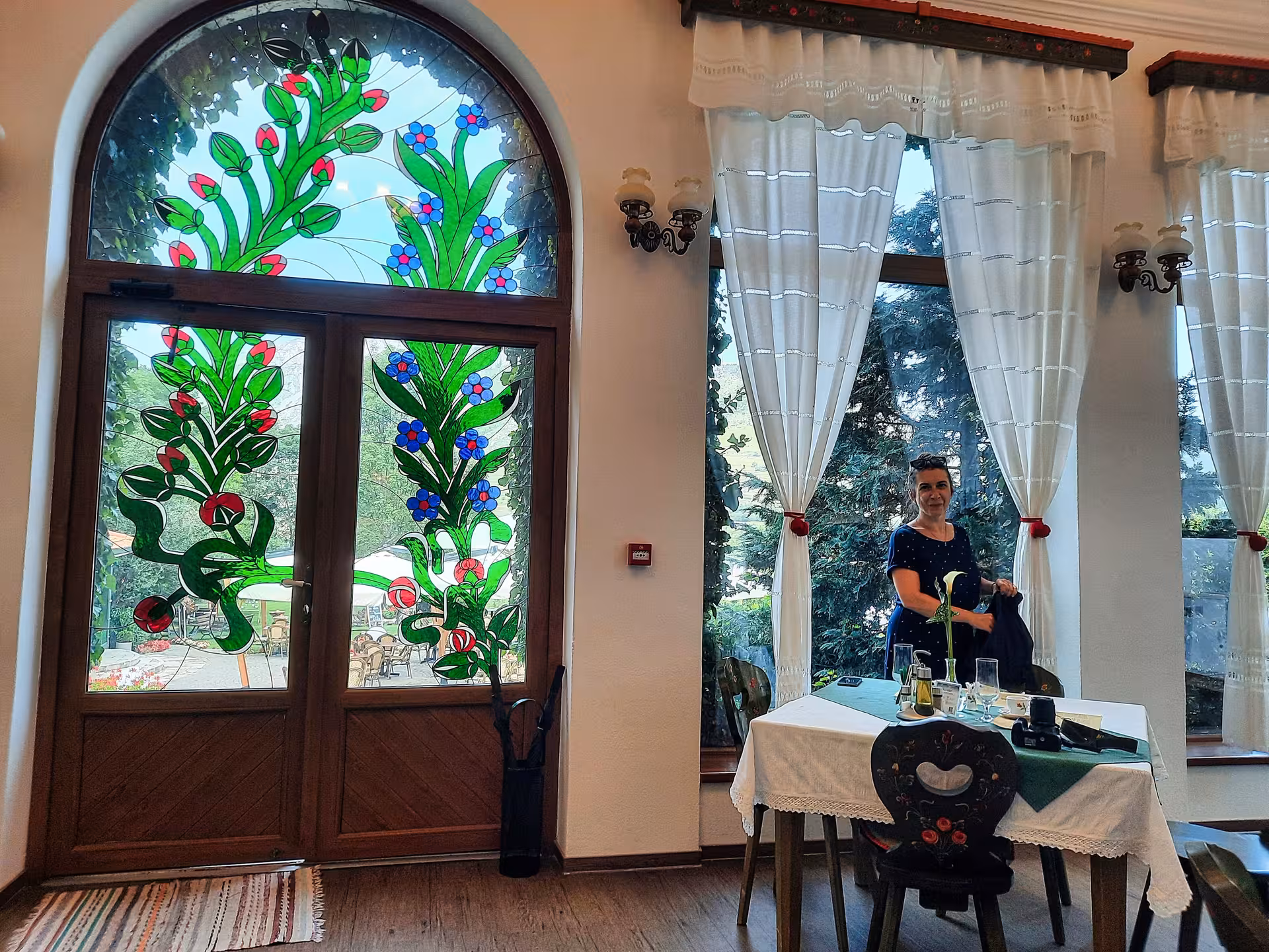 Elegant restaurant interior with floral stained glass doors and a welcoming host in Rimetea Apuseni Mountains dinner tour
