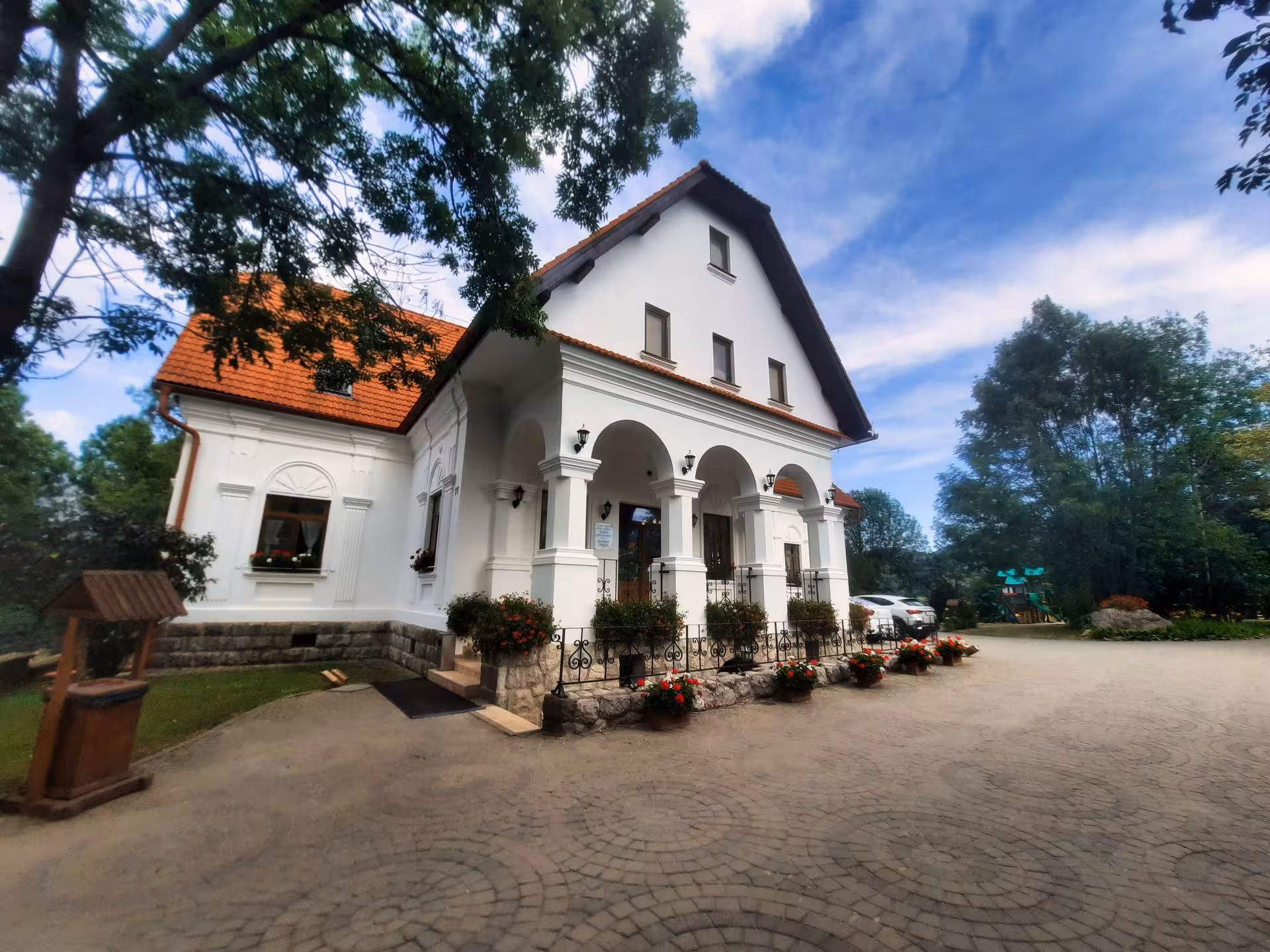 Elegant white heritage guesthouse with arched porch and red tile roof for guided dinner tours in Rimetea Apuseni Mountains