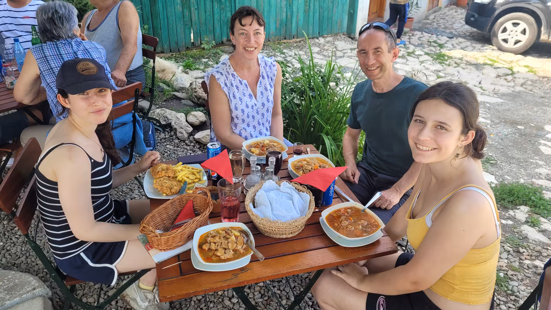 Family enjoying traditional Romanian lunch at outdoor restaurant during Rimetea village day trip from Cluj-Napoca