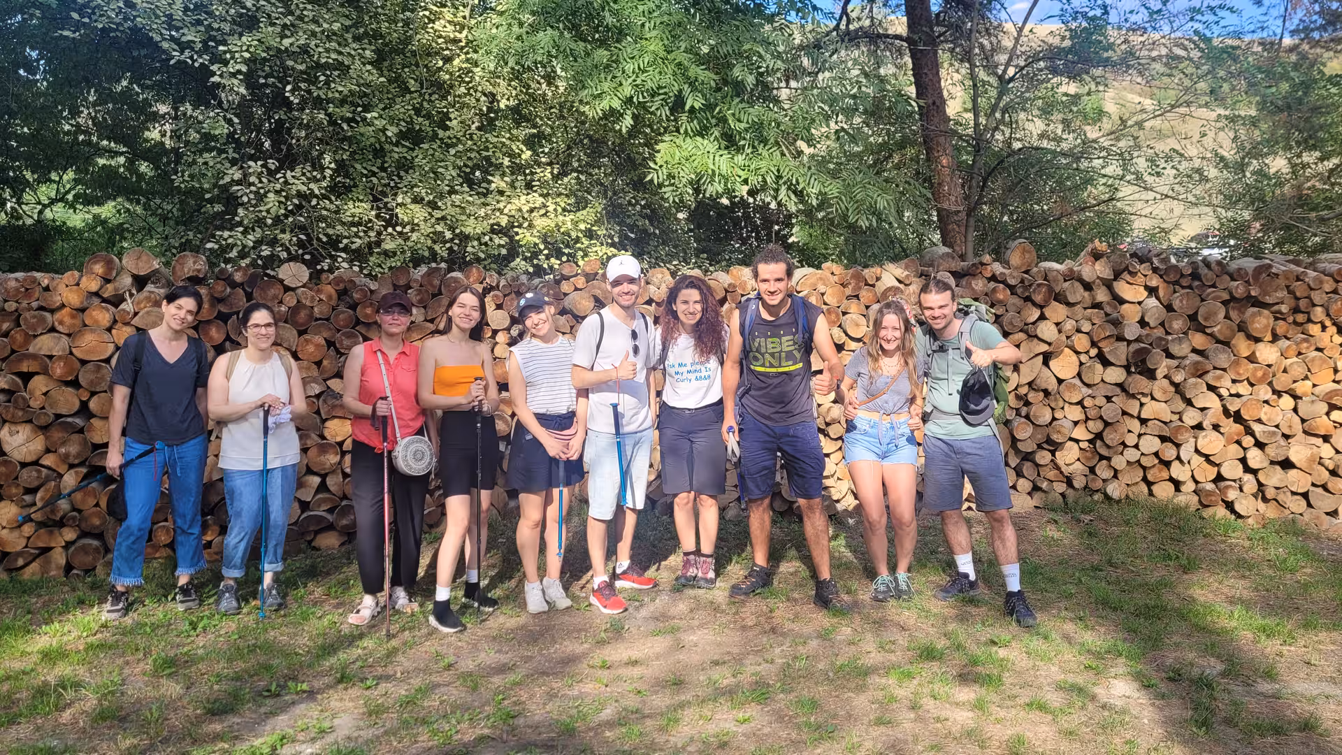 Group of hikers posing in front of large stacked firewood wall during Rimetea village day trip