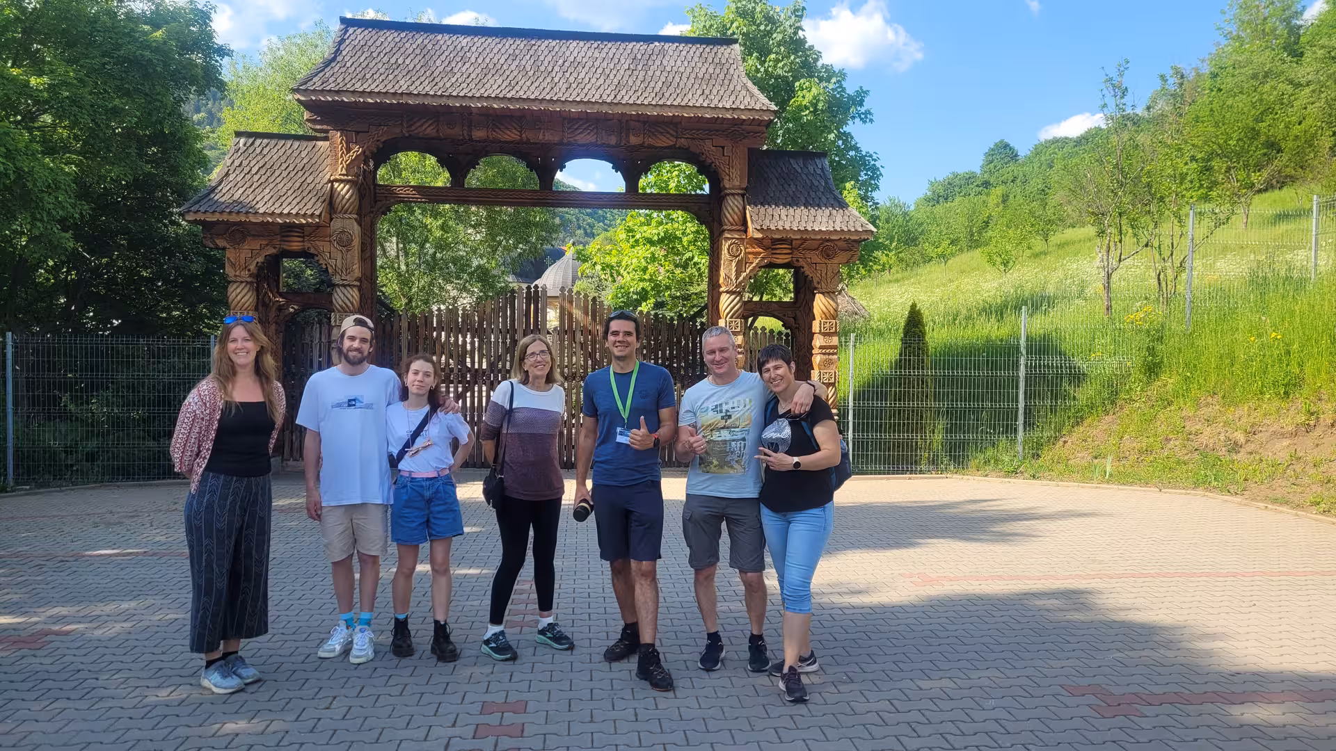 Tour group posing in front of ornate carved wooden gate at Rimetea Village on day trip from Cluj-Napoca