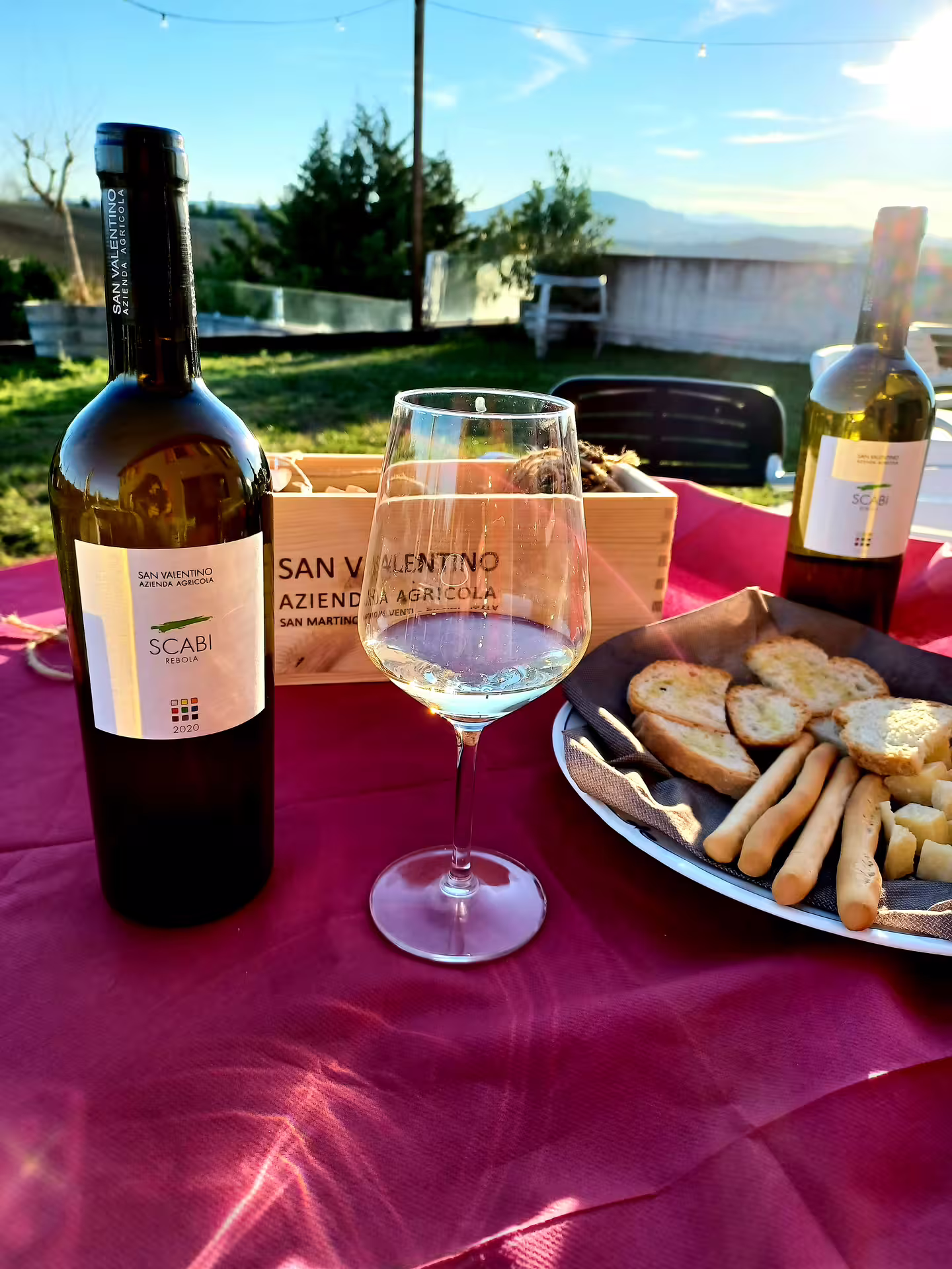 Outdoor wine tasting setup with San Valentino DOC wine, glass, and appetizers in Rimini's scenic ambiance.
