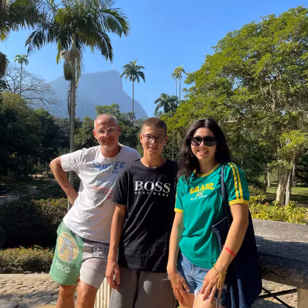 Group of friends exploring the vibrant palm-lined pathways of Rio's Botanical Garden under a sunny sky.