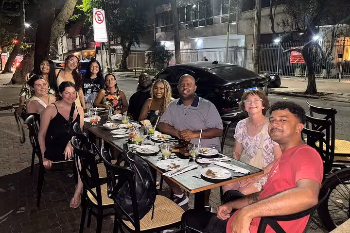Group enjoying a lively night out dining on Brazilian cuisine at a street-side restaurant.