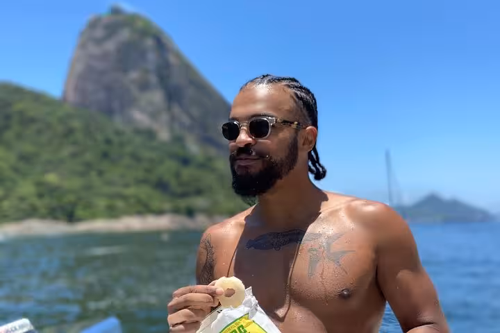 Guest enjoying snacks on Rio de Janeiro catamaran tour, open bar cruise with Sugarloaf Mountain views