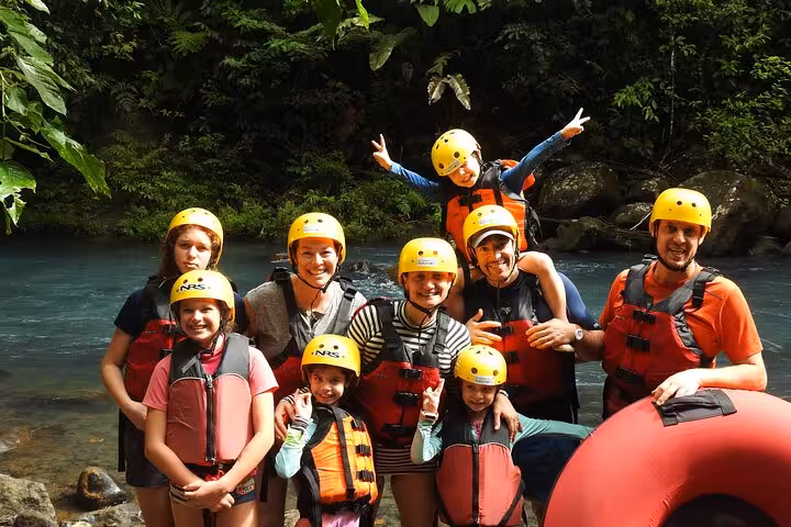 Group of smiling adventurers ready for a hiking and tubing tour in Rio Celeste with helmets and life jackets.