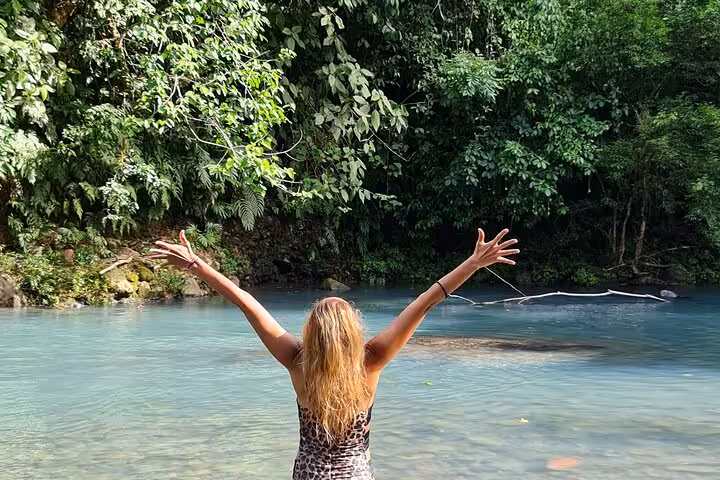 Traveler enjoying the vibrant turquoise waters of Rio Celeste surrounded by lush tropical rainforest on a nature hike.