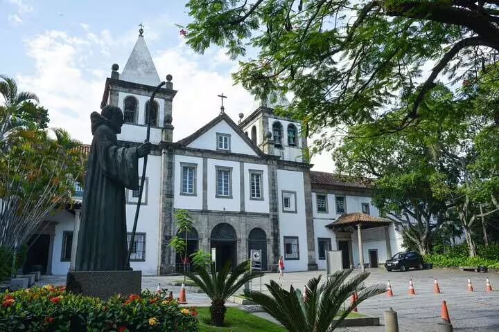 Historic church with twin bell towers and a prominent statue in Rio's downtown, highlighting architectural heritage.