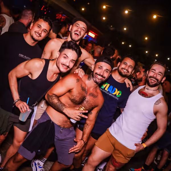 Joyful group of men at Rio Gay Nightlife party under twinkling lights, embodying festive spirit.