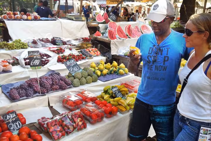 Couple exploring vibrant tropical fruit selection at a bustling Rio market.