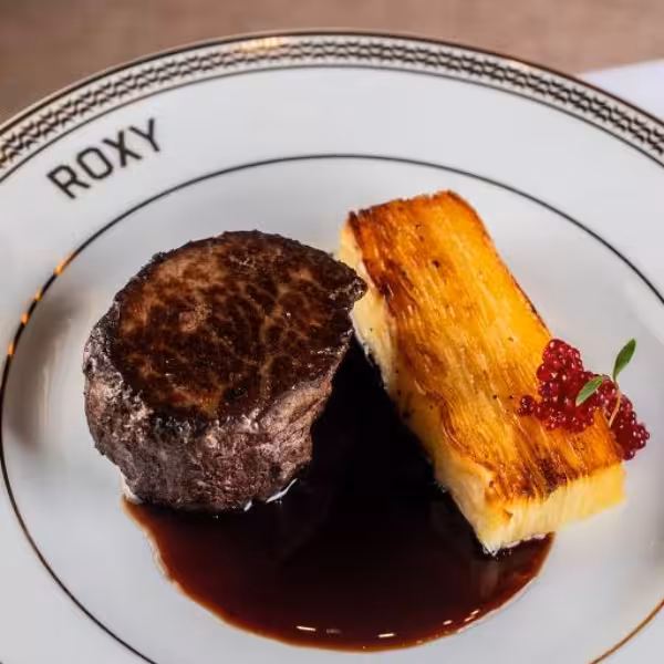Gourmet steak with sauce and a side of potato gratin served at Roxy Copacabana cultural dinner show.