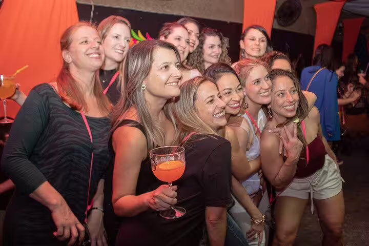 Smiling group of friends posing with drinks at a bustling bar, capturing the essence of Rio's vibrant nightlife scene.