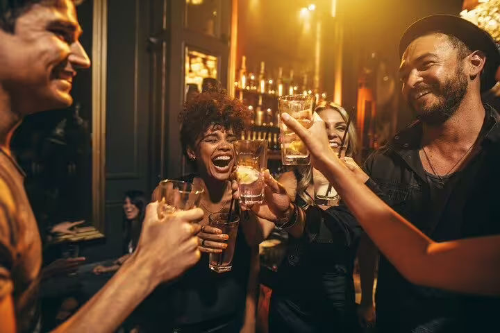 Group of friends enjoying cocktails and laughter at a stylish Rio de Janeiro bar on the nightlife tour.