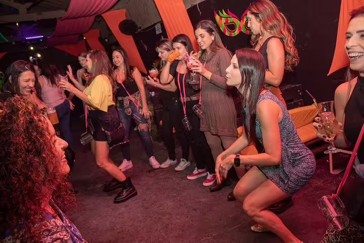 Group of women dancing and enjoying vibrant cocktails at a lively club during the Rio Nights Unleashed nightlife tour.