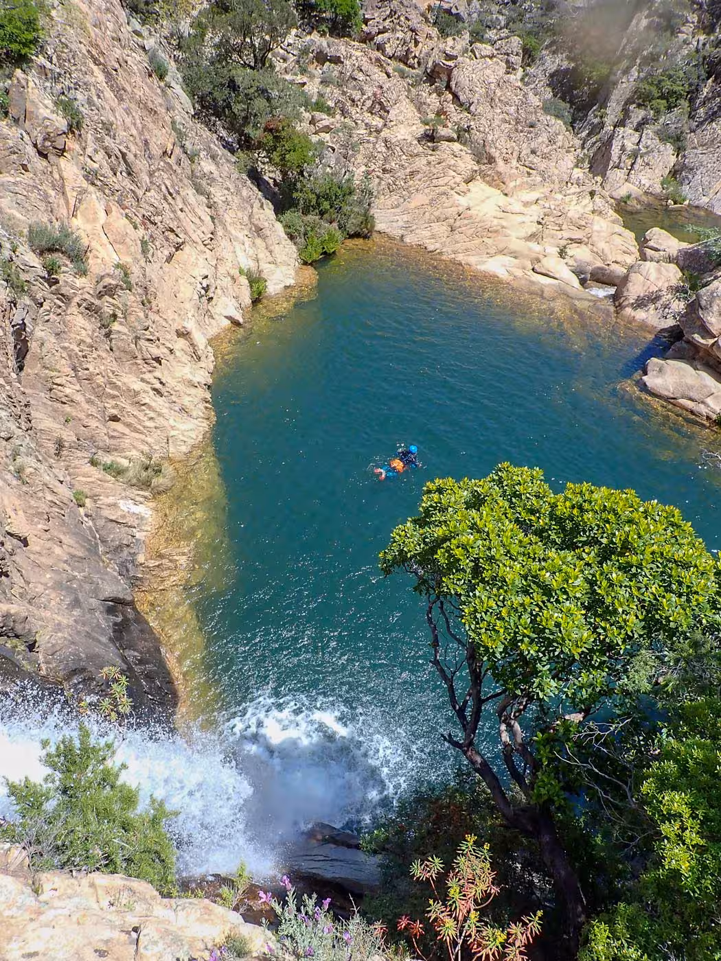 Aerial view of Rio Pitrisconi's turquoise pool surrounded by rugged cliffs, ideal for canyoning in San Teodoro.