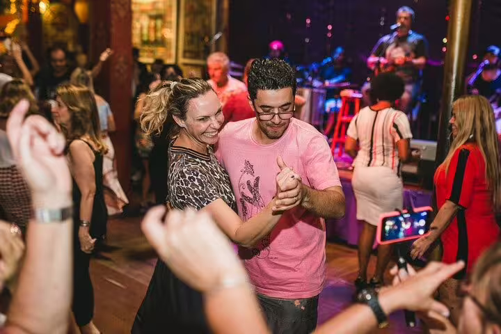 Couple dancing joyfully amidst a lively crowd at a Rio de Janeiro samba night club during the nightlife tour.